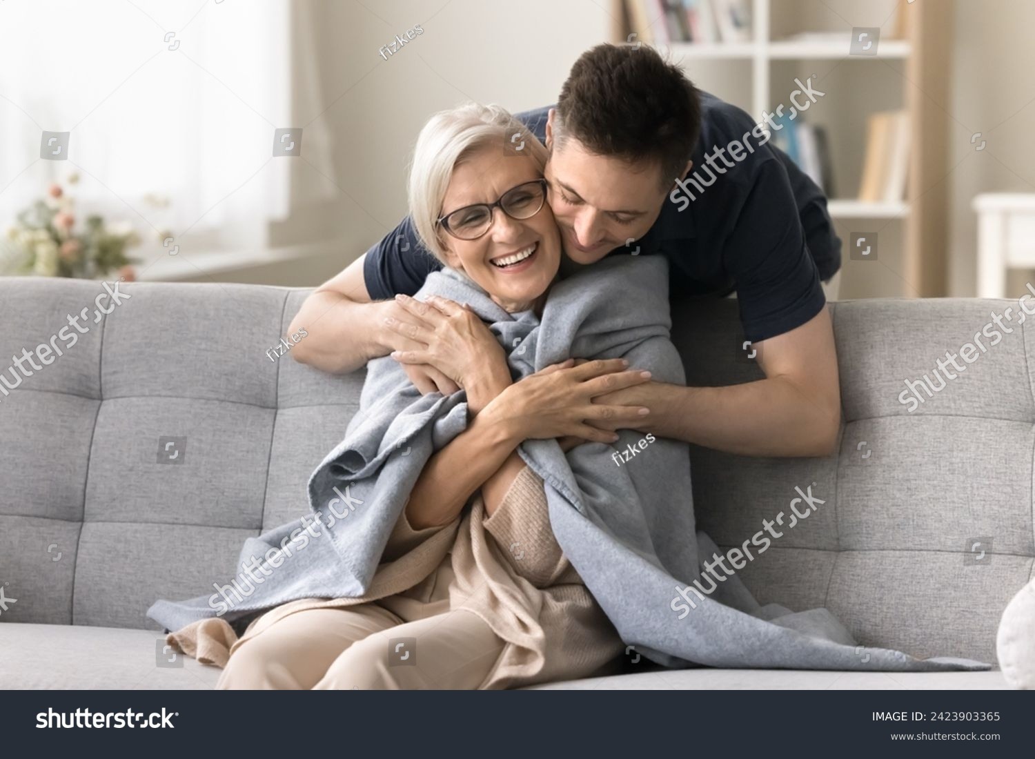 stock-photo-positive-young-adult-son-man-caring-for-happy-elderly-mature-mother-sitting-on-comfortable-sofa-2423903365